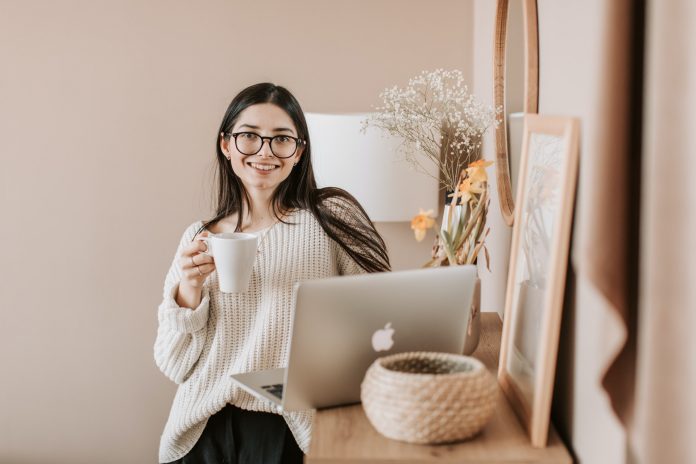 woman-standing-with-a-cup-of-coffee-near-a-laptop-4050391